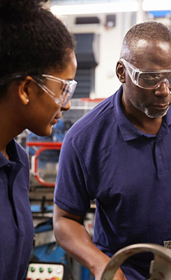 Two people wearing uniforms and protective eye glasses at work.