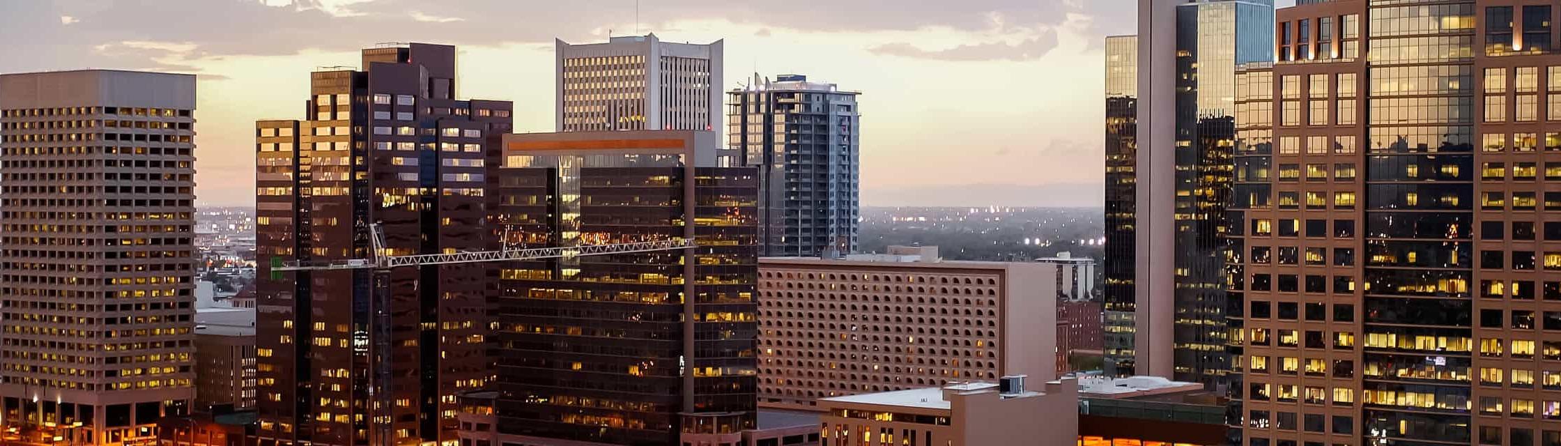 Tall city buildings illuminated at night, with glowing windows.