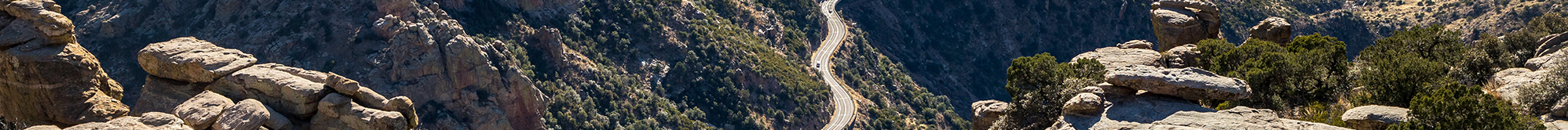 A winding road curving around shrub-covered mountains.