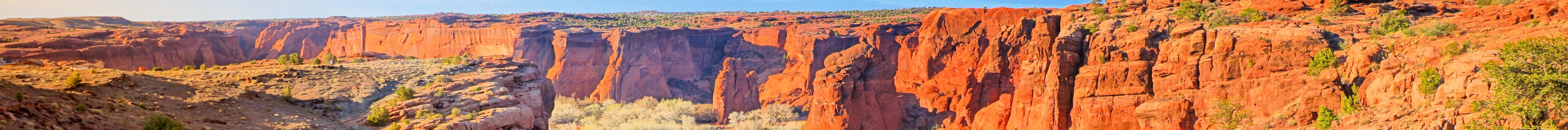 Steep red cliffs and a winding canyon floor in a desert landscape.