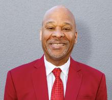 Professional headshot of a person in a red blazer.