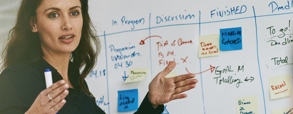 Woman standing before a whiteboard displaying handwritten notes.