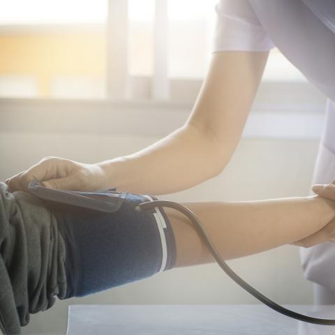 A nurse placing a blood pressure cuff on a patient.