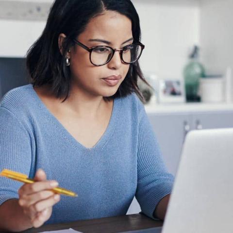 A woman wearing eyeglasses working on a laptop computer.